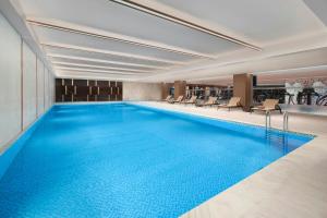 a large swimming pool in a hotel lobby with chairs at Sheraton Tengzhou in Zhaozhuang