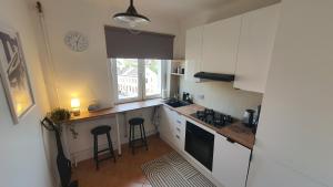 a kitchen with white cabinets and a counter with stools at Apartament Witosa in Tarnów