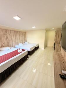 a room with two beds and a flat screen tv at Hotel Estação Express in Curitiba
