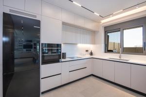 a kitchen with white cabinets and a large window at Villa Nectar in Kounoupidhianá