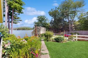 a garden with a house on the shore of a lake at King Birch Lake Home, Unit 7 in Alton