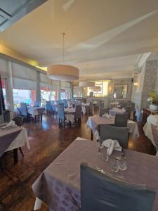 a dining room with white tables and chairs and windows at Hôtel De France in Thann