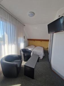 a hotel room with a bed and a chair and a television at Hôtel De France in Thann