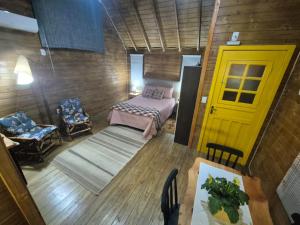 a room with a bed and a yellow door at Cabanas Laura in São Francisco de Paula +2 photos