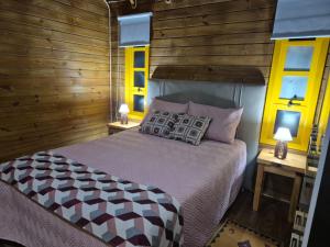 a bedroom with a bed with wooden walls and windows at Cabanas Laura in São Francisco de Paula
