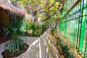 a walkway next to a green fence with a tree at Time Stay Hotel in Yerevan