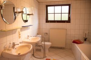 a bathroom with two sinks and a toilet and a window at Haus Heinzmann in Bad Schonborn