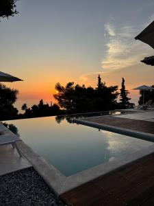 a swimming pool with a sunset in the background at Limestone House in Athani