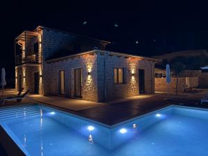 a villa with a swimming pool at night at Limestone House in Athani