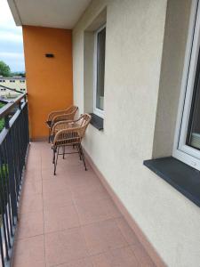 three chairs sitting on a balcony with windows at Apartament Kaszmirowy in Gorlice