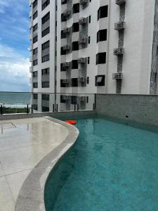 a swimming pool in front of a tall building at Beach Class Executive - Flats no Pina por Yolo in Recife