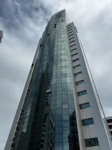 a tall glass building against a cloudy sky at Beach Class Executive - Flats no Pina por Yolo in Recife +38 photos