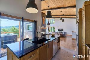 a kitchen with a counter top and a living room at Chalet L'Ascension in Saint-Philémon