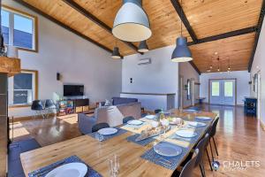 a dining room with a large wooden table in a living room at Chalet L'Ascension in Saint-Philémon