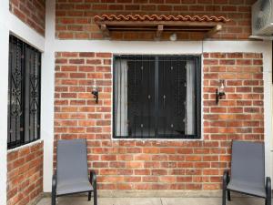 two chairs sitting in front of a brick wall at Casa ciruelo in Las Varas