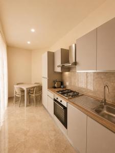 a kitchen with white cabinets and a table and a sink at Villa Elysia Tropea in Tropea
