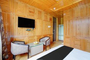 a bedroom with a tv and two chairs and a table at Palette Hotel Regency Valley View Pahalgam By CheckIn in Batakūt