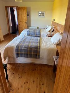 a bedroom with two beds and a wooden floor at Behan's Lodge in Doonbeg +3 photos