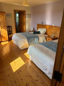 a bedroom with two beds and a wooden floor at Behan's Lodge in Doonbeg