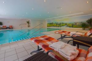a large swimming pool with lounge chairs and a swimming pool at NewLivingHome Residenzhotel Hamburg in Hamburg