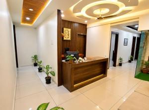 an office lobby with a reception desk and potted plants at Parth Paradise Hotel in Indore