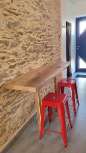 a wooden table with two red stools in front of a stone wall at studio douillet en centre bourg in La Plaine-sur-Mer
