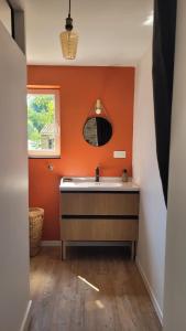 a bathroom with a sink and an orange wall at studio douillet en centre bourg in La Plaine-sur-Mer