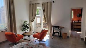 a living room with orange chairs and a table and a window at studio douillet en centre bourg in La Plaine-sur-Mer