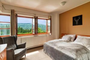 a bedroom with a bed and a chair and windows at Hotel Oddech in Pec pod Sněžkou +114 photos