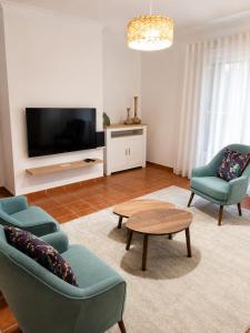 a living room with two chairs and a table and a tv at Casa com Alma by LovelyStay in Fátima