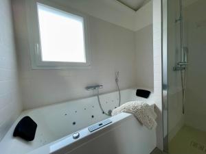 a white bathroom with a tub and a window at Paradisier, clim, grande terrasse, balneo, Parc des Oiseaux in Villars-les-Dombes +14 photos