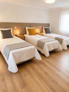 three beds in a room with wood floors at Casa com Alma by LovelyStay in Fátima