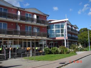 ein rotes Gebäude mit Balkonen und Tischen davor in der Unterkunft Hotel Goor und Apartmenthaus in Lauterbach