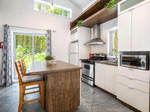 a kitchen with white cabinets and a wooden counter top at Chalet Chic et Spa - St-Come in Saint Come