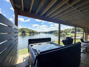 a hot tub on a porch with a view of a river at Lakeside, Water-view, 7 miles to Ark, 4BR for 14 in Williamstown