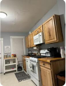 a kitchen with wooden cabinets and a white stove top oven at Charming Cozy Getaway in Oneonta