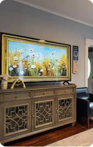 a large painting of flowers on top of a wooden cabinet at Charming Cozy Getaway in Oneonta
