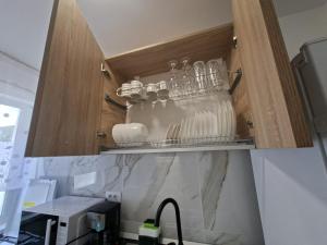 a kitchen cabinet with some dishes in it at Codruta Home in Râmnicu Vâlcea +5 photos