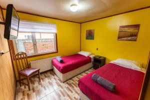 a bedroom with two beds and a chair and a window at Nikos II Adventure in Puerto Natales
