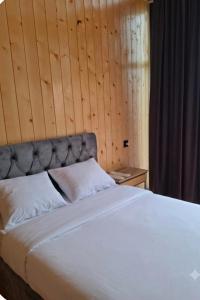 a bedroom with a large white bed with a wooden wall at AnArt rezort in Vanadzor
