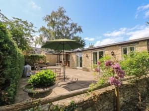 a patio with a table and an umbrella at Meadow Lodge in Cirencester