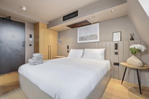 a bedroom with a large white bed and a vase of flowers at The Maida Hotel in London
