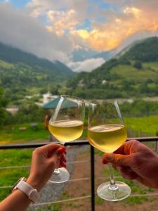 two people holding glasses of white wine with a view at Mountain Shadow Cottage in Racha in Ghebi