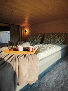 a bed with a tray with two cups and fruit on it at Tiny Vinkel - Domki Tiny House Jastarnia in Jastarnia