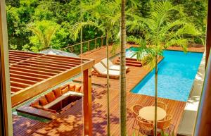 a view of a deck with a pool and palm trees at Green House Praia do Forte- 4 Suítes Premium in Mata de Sao Joao