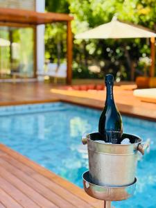 a bottle of wine in a bucket next to a swimming pool at Green House Praia do Forte- 4 Suítes Premium in Mata de Sao Joao