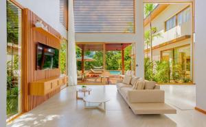 a living room with a couch and a table at Green House Praia do Forte- 4 Suítes Premium in Mata de Sao Joao +19 photos