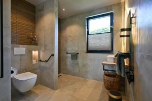 a bathroom with a toilet and a sink and a window at Bij Corine, bed en zorg in Altforst +21 photos