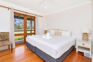 a white bedroom with a large bed and a window at Shiraz Vineyard Estate in Pokolbin