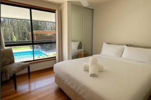 a bedroom with a bed and a window with a pool at Shiraz Vineyard Estate in Pokolbin